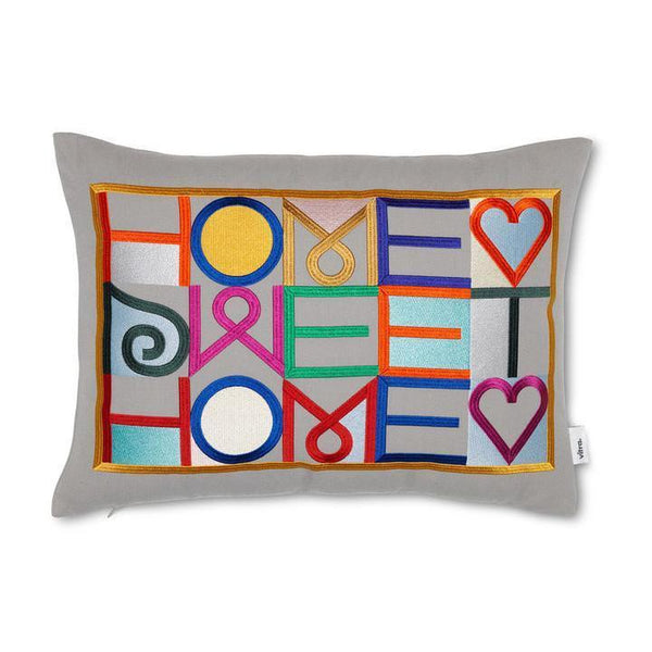 Colorful decorative pillow with vibrant letters and symbols on a grey background, featuring a playful patchwork design.