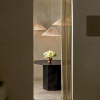 Warm neutrals with soft golden tones, featuring a geometric black table and textured hanging lamps.