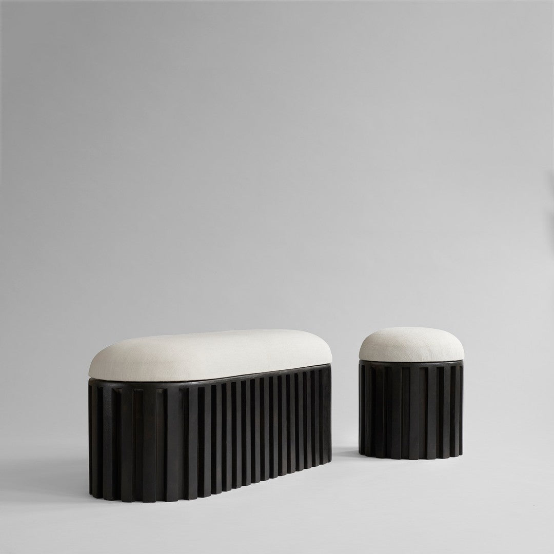 Black striped bench and stool with cream upholstery, showcasing modern design and neutral color palette.