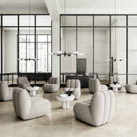 Light gray upholstered chairs and tables with soft curves in a modern, minimalist setting. Black accents enhance the design.