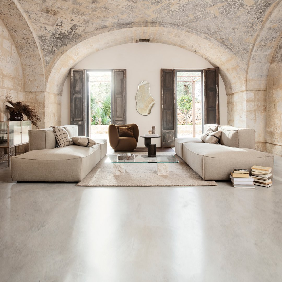 Neutral beige sofas with textured fabric, set on a light gray floor, complemented by earthy brown and soft white accents.