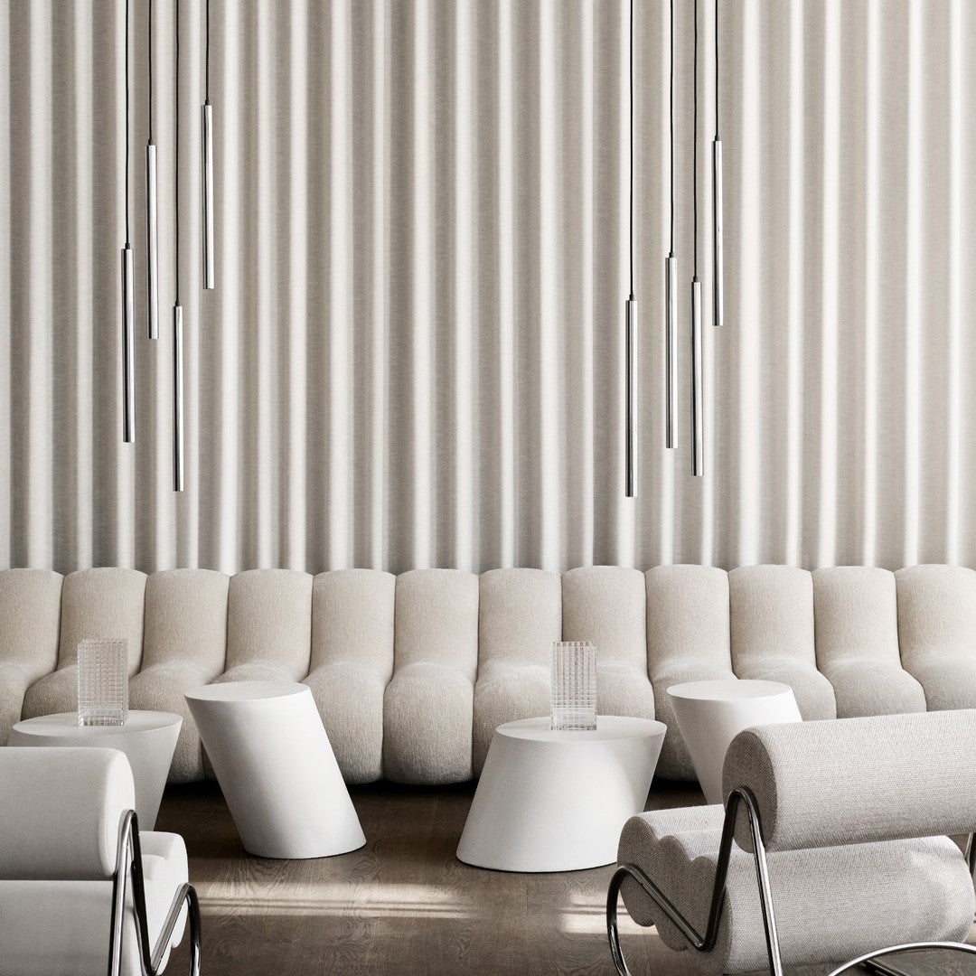 Modern lounge area featuring soft beige and white tones with subtle textures and sleek silver pendant lights.