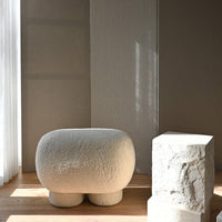 Textured cream-colored stool against soft beige walls, highlighting minimalist design and natural hues.
