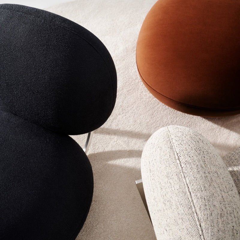 Black, brown, and white textured poufs on a soft beige carpet, showcasing a modern, minimalist design.