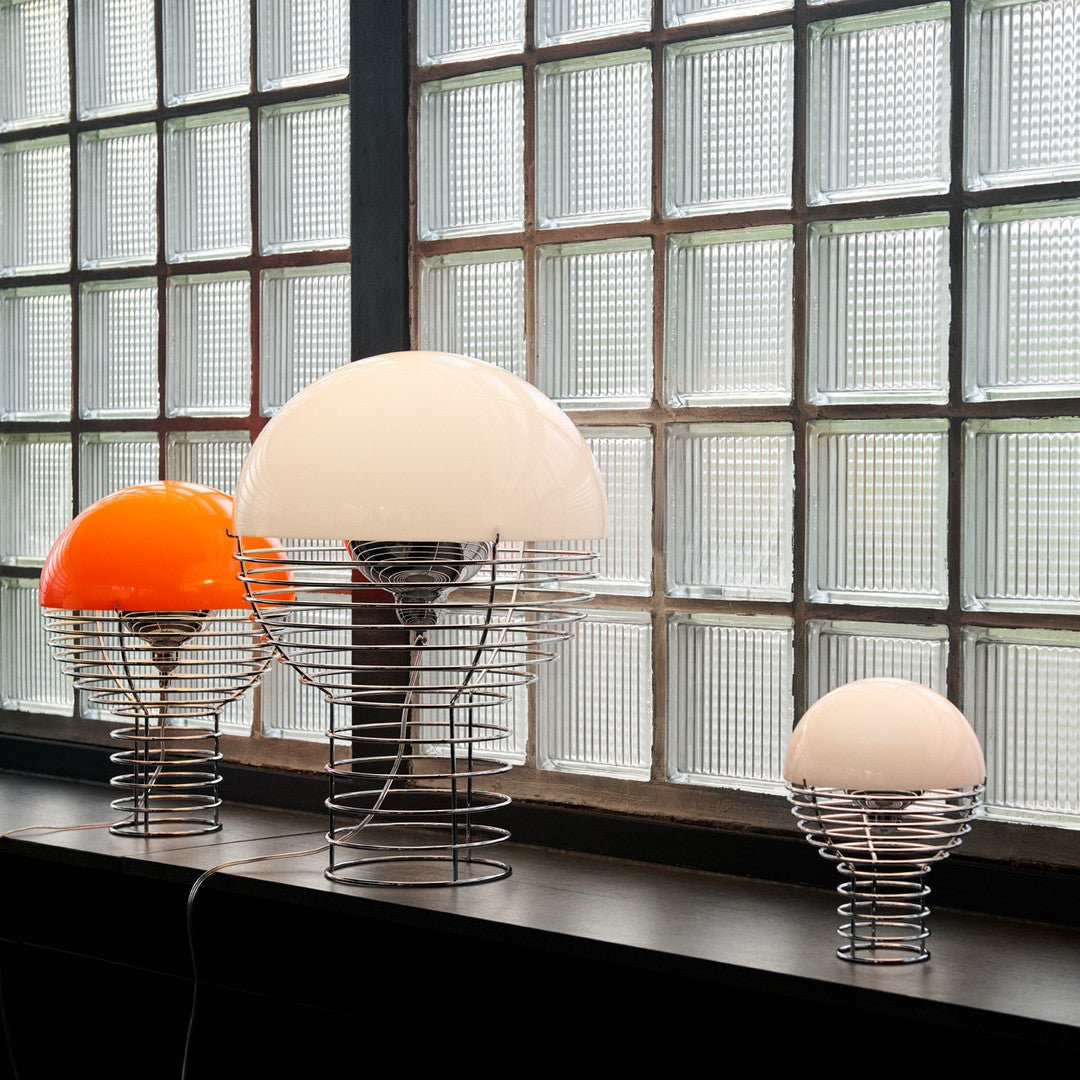 Colorful modern lamps with orange and white dome shades, featuring stylish wire bases, arranged by size.