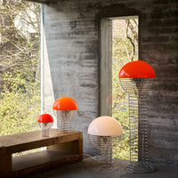 Colorful modern lamps featuring vibrant orange and soft white domes, set against a minimalist concrete backdrop.