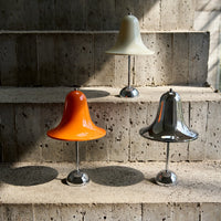 Colorful bell-shaped lamps in orange, cream, and metallic silver on a textured stone staircase.