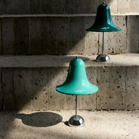 Modern teal bell-shaped lamps with chrome bases, highlighting sleek design and vibrant color against a textured backdrop.