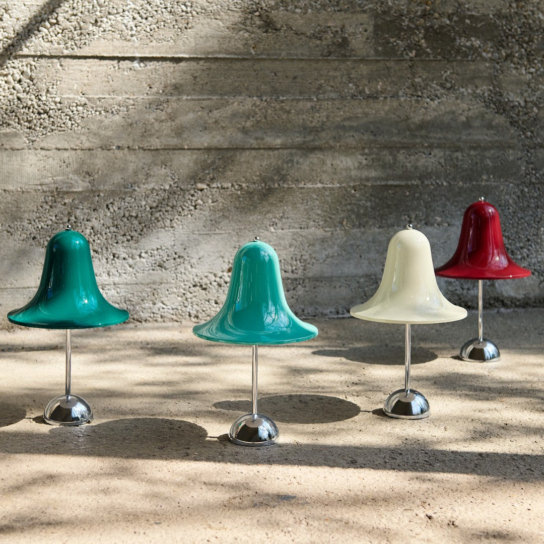 Colorful bell-shaped decor in teal, cream, and red with shiny chrome bases, set against a textured gray background.