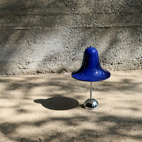 Glossy blue bell-shaped design on a sleek chrome base, set against a textured gray background.