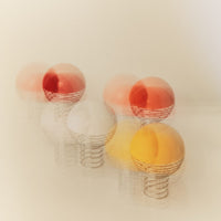Colorful ping pong balls in red, orange, yellow, and white with a swirling motion effect on a soft beige background.