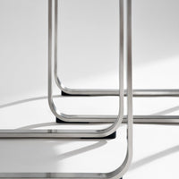 Stylish silver metal frame with sleek curved edges and contrasting black feet on a soft gray background.