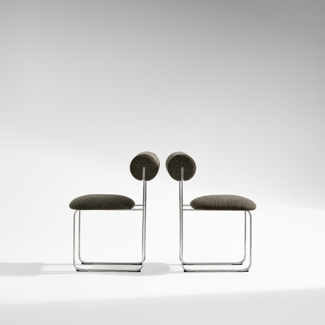 Modern gray upholstered chairs with circular backrests and sleek metal frames, perfect for contemporary decor.