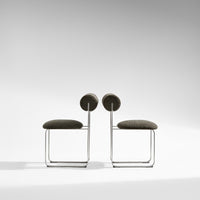 Modern gray upholstered chairs with circular backrests and sleek metal frames, perfect for contemporary decor.