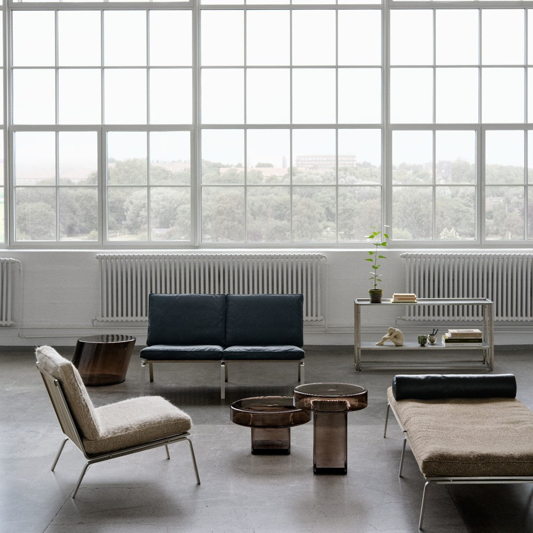 Modern furniture arrangement featuring dark blue, soft beige, and metallic bronze accents against a bright, airy backdrop.