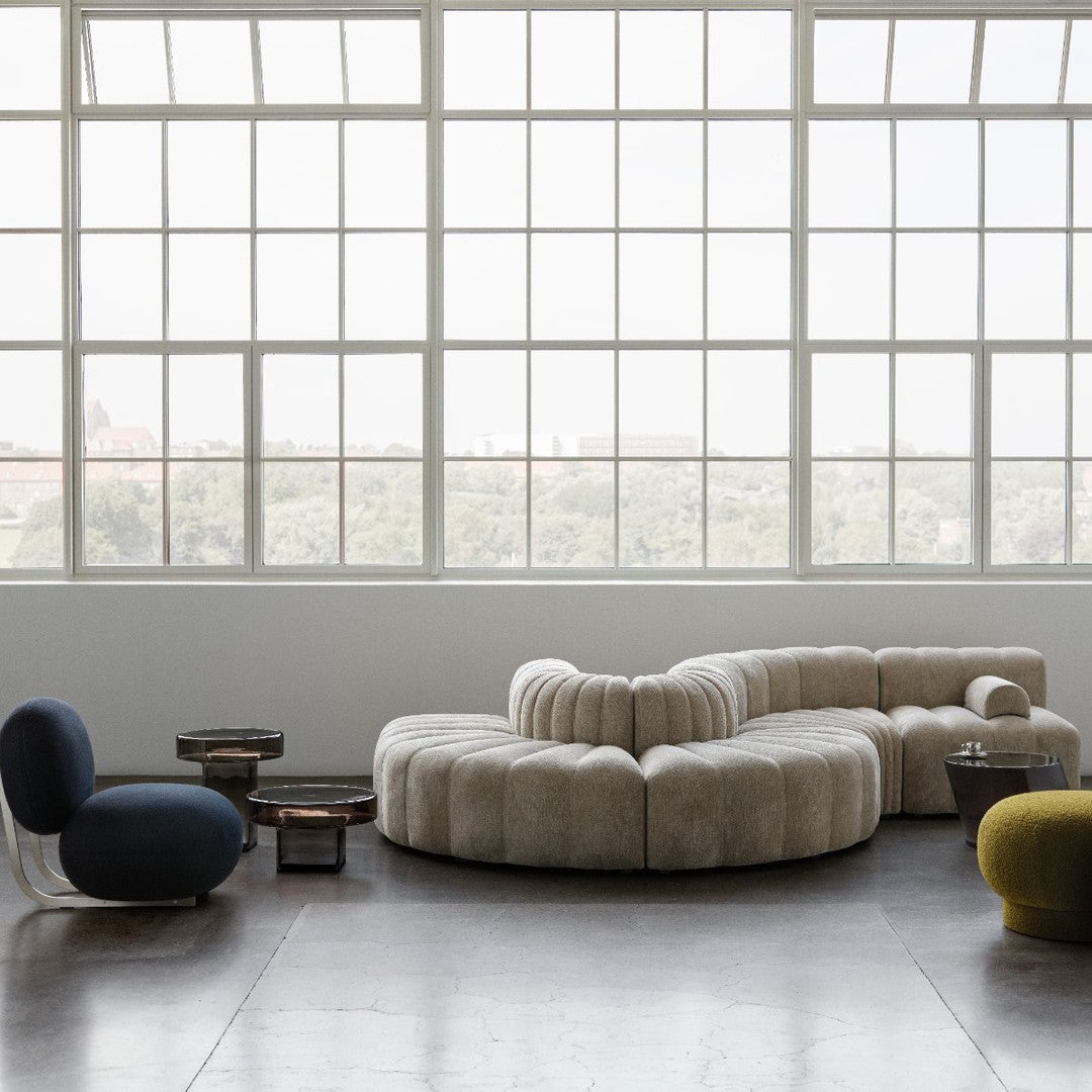 Cozy beige sectional sofa with ribbed texture, paired with dark blue and vibrant green accent chairs and tables.