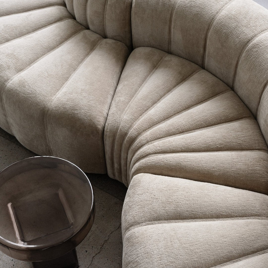 Textured beige couch with a unique fan pattern, complemented by a sleek, dark metallic side table.