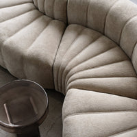 Textured beige couch with a unique fan pattern, complemented by a sleek, dark metallic side table.