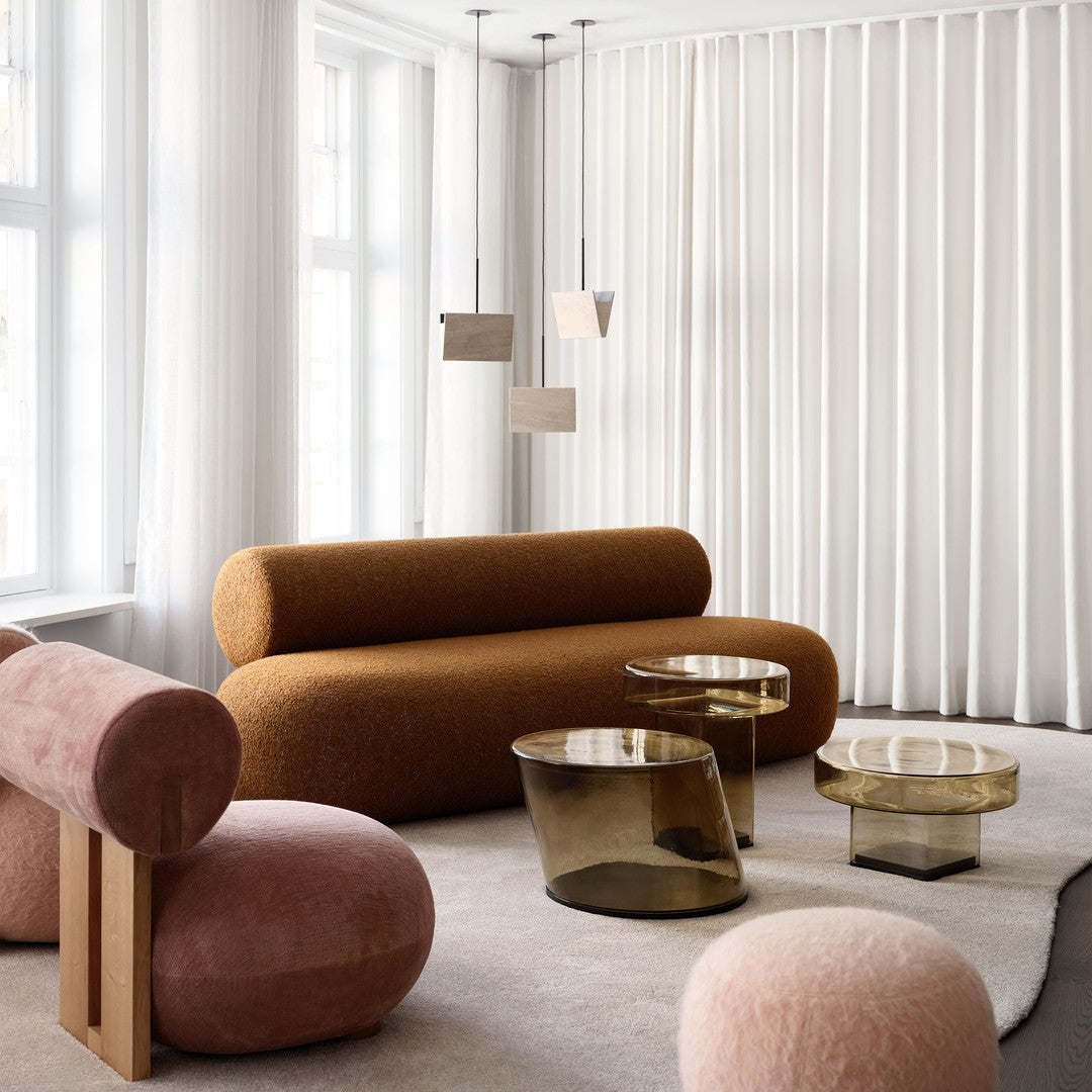 Modern interior with a rust-colored sofa, pink accent chairs, and gold-tinted glass tables against white curtains.