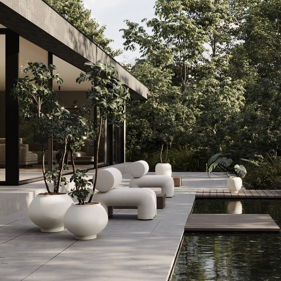 Minimalist outdoor seating and planters in white, grey, and natural wood, surrounded by lush green foliage.