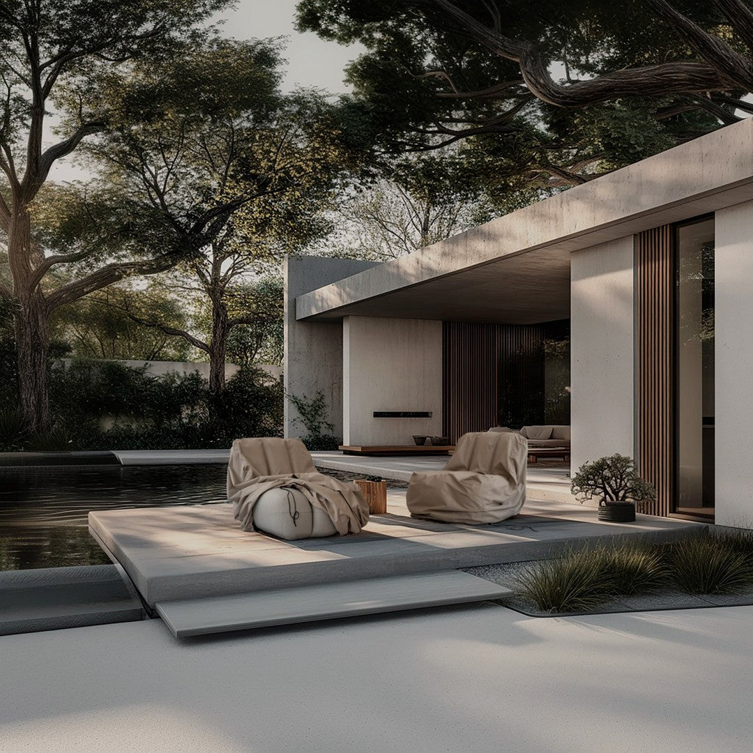 Neutral beige bean bag chairs on a sleek grey patio, surrounded by lush green foliage and minimalist architectural design.