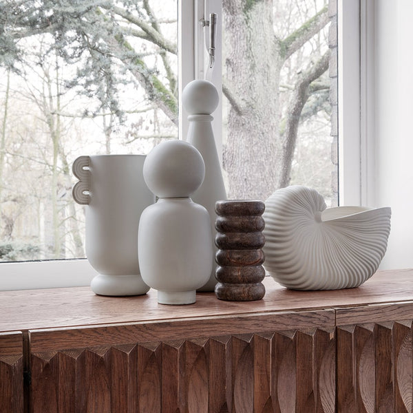 Set of white vases with smooth and textured patterns displayed on wood, complementing a minimalist decor style.