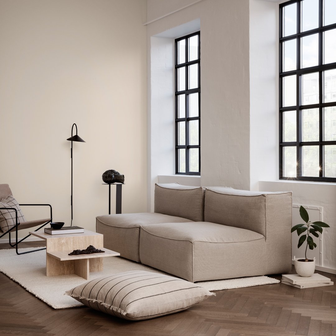 Light beige sectional sofa with textured fabric, paired with a minimalist cream rug and natural wood accents.