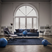 Navy blue sofa with gray and purple cushions, set on a textured navy rug, complemented by blue decorative balls.