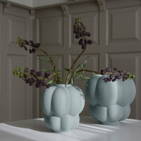 Two textured vases in soft mint green, featuring a modern bubble pattern, with purple flowers.