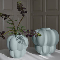 Two soft blue textured vases with organic shapes and subtle shadows, showcasing stylish design and elegance.