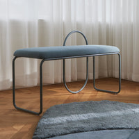 Light blue upholstered bench with minimalist design and a sleek gray metal frame, set against a soft rug.