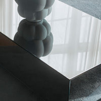 Reflective rectangular coffee table with a smooth, glossy surface and soft gray accents on a textured blue rug.