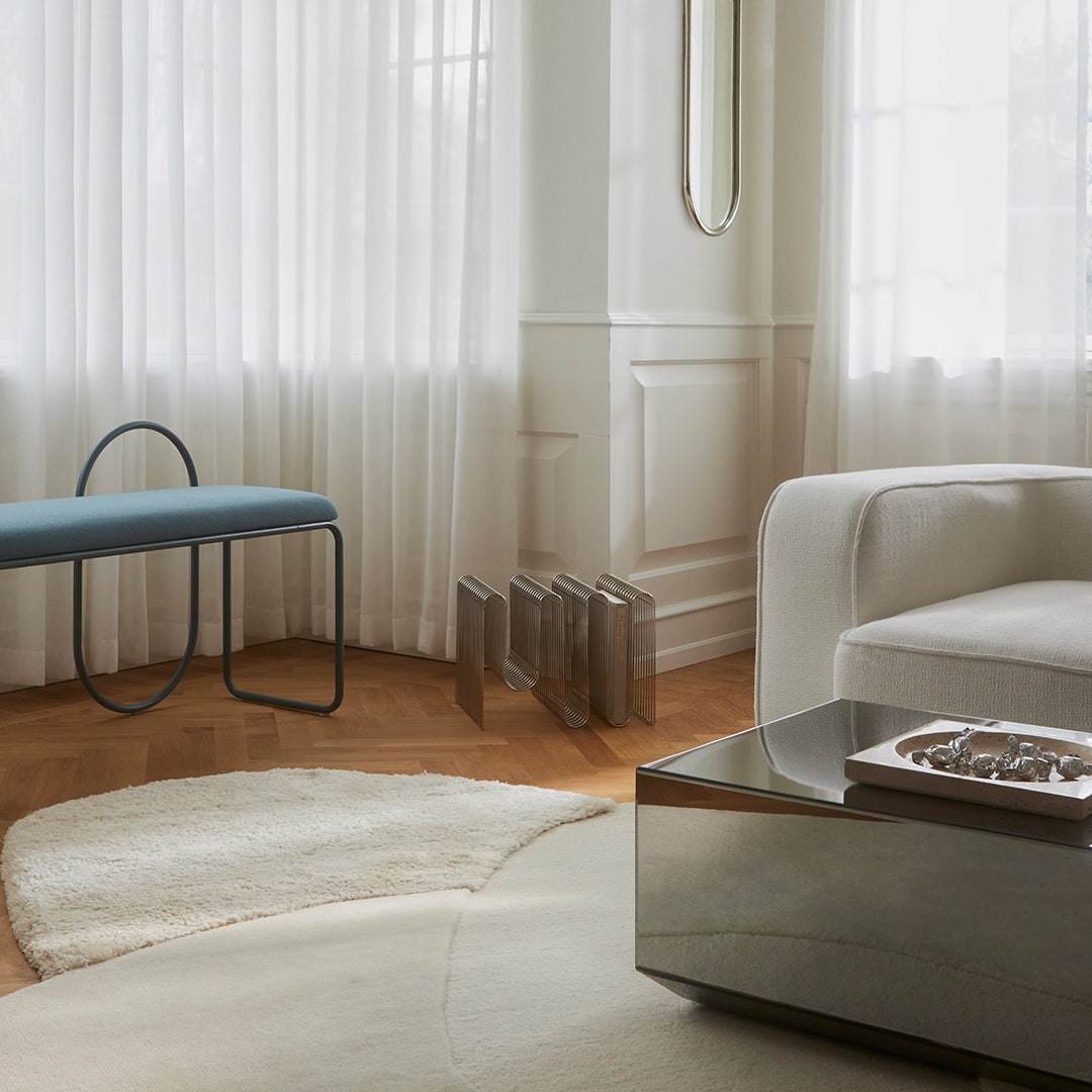 "Modern living room featuring soft beige shades, a blue bench, and subtle geometric patterns in the decor."