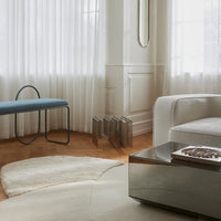 "Modern living room featuring soft beige shades, a blue bench, and subtle geometric patterns in the decor."
