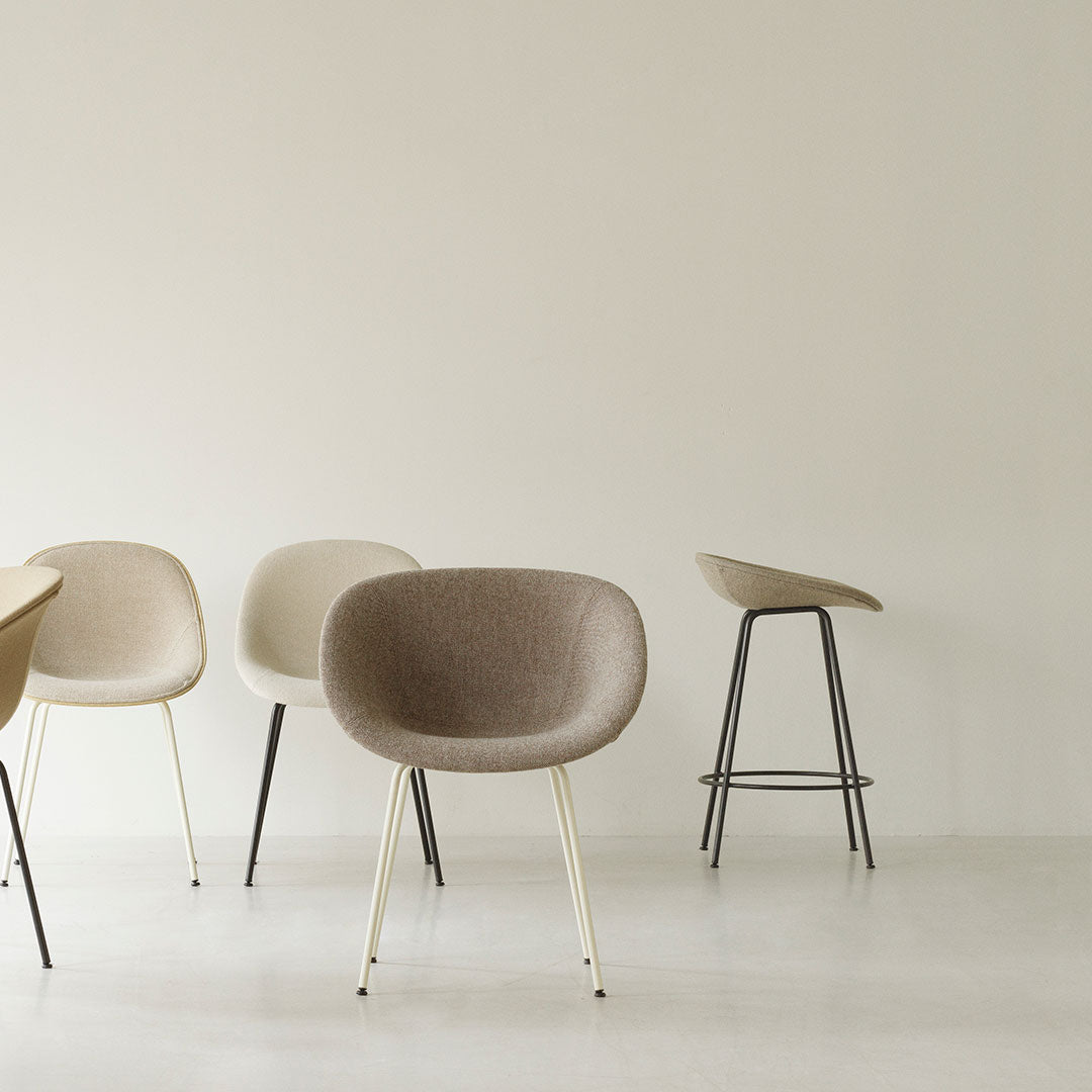 Minimalist chairs in soft beige and taupe tones with sleek metal legs, set against a neutral background.