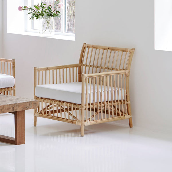 Natural bamboo chair with a neutral white cushion, featuring an open slat pattern for a modern aesthetic.