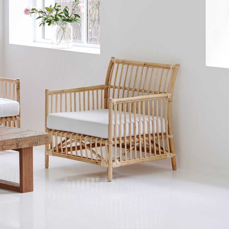 Natural bamboo chair with a neutral white cushion, featuring an open slat pattern for a modern aesthetic.