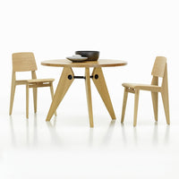 Scandinavian-style round table and two chairs in light natural wood with minimalistic design.