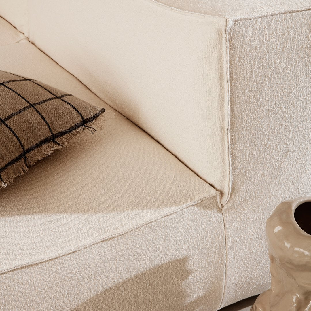 Beige textured sofa with a grid-patterned throw pillow, creating a cozy, modern aesthetic.