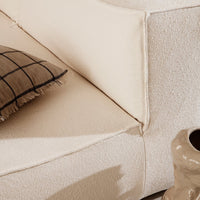 Beige textured sofa with a grid-patterned throw pillow, creating a cozy, modern aesthetic.