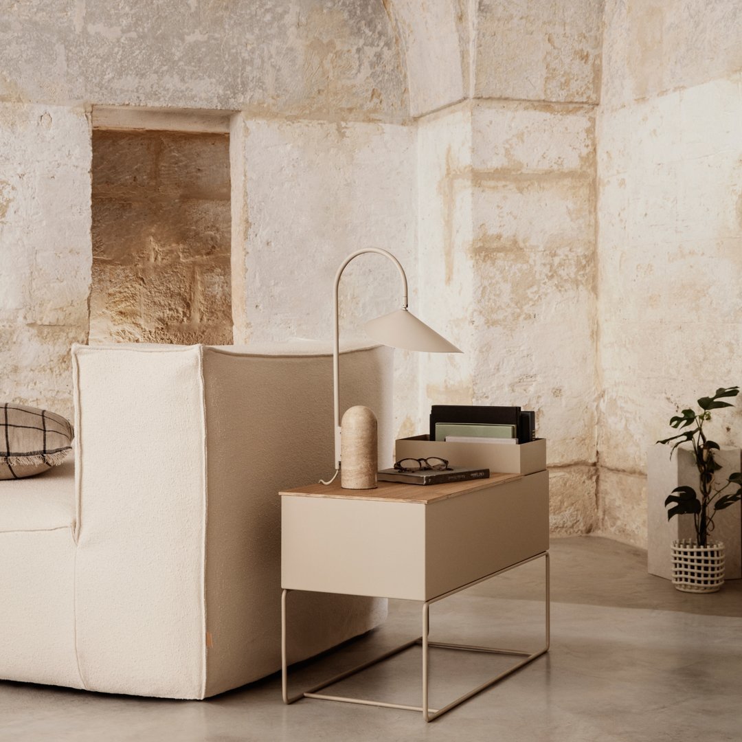 Beige modern side table with minimalist design, complemented by neutral tones and smooth surfaces, set against textured walls.