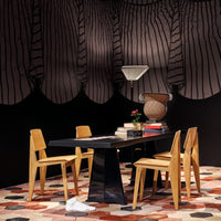Black and white striped curtains, warm wood chairs, and a hexagonal pattern rug in earthy tones. Modern dining space decor.