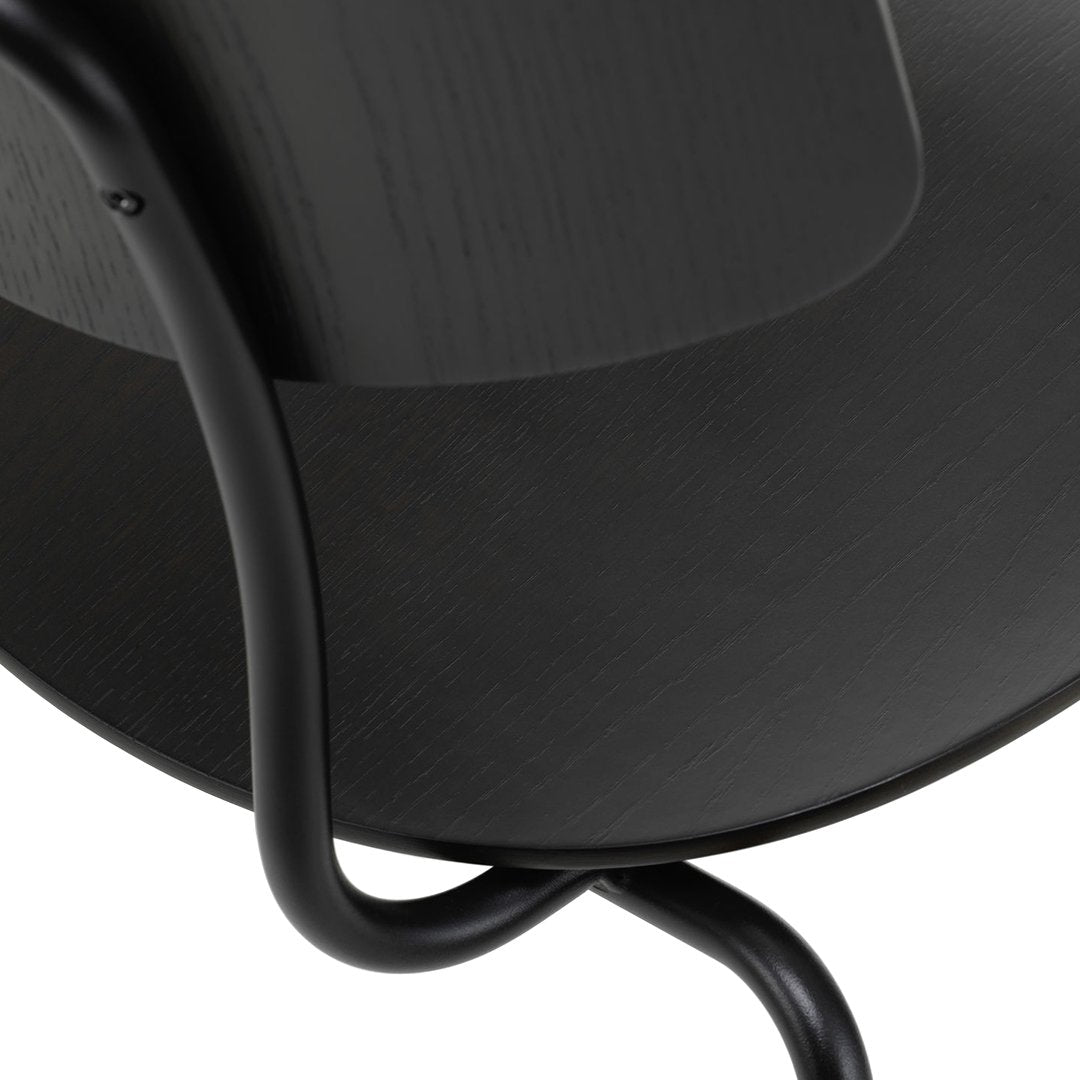 Black curved chair featuring a smooth wooden surface and sleek black metal legs. Modern minimalist design.