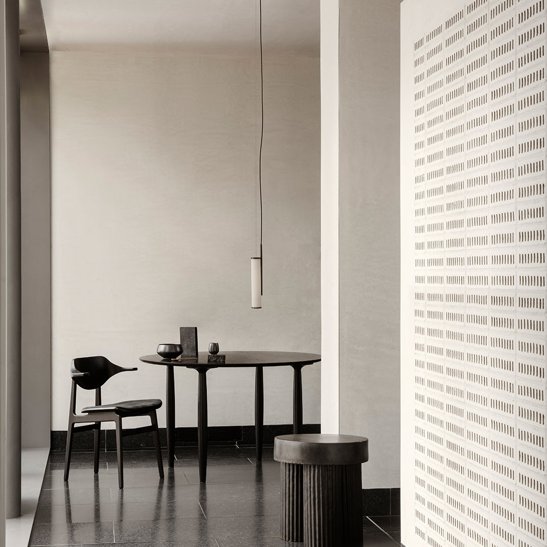 Modern black furniture with a minimalist design, set against a soft beige wall and patterned white accents.