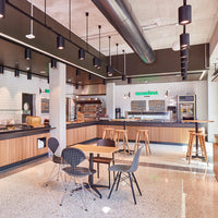 Modern café interior featuring neutral tones, sleek black accents, and warm wooden textures. Elegant seating design.