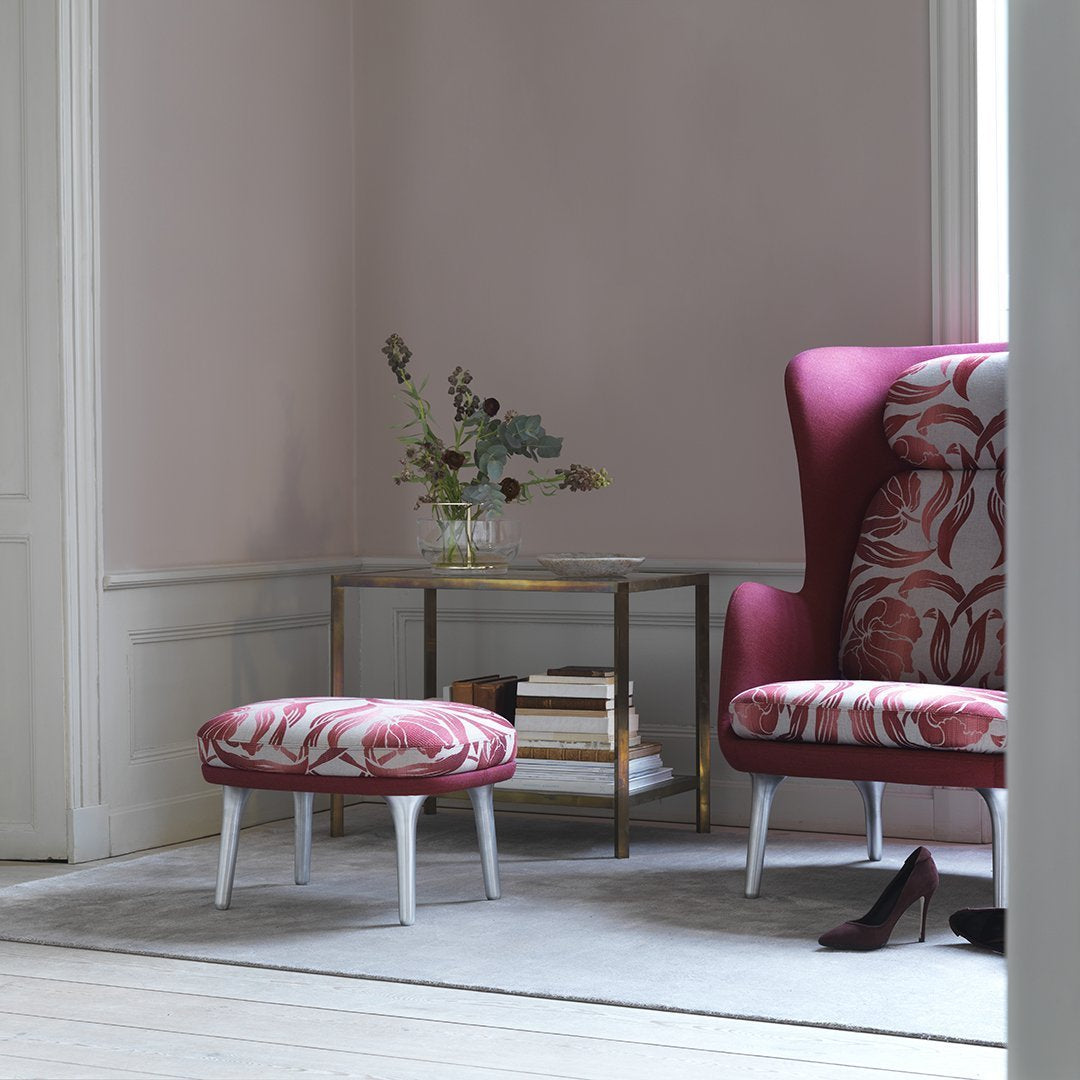 Pink and white patterned armchair and ottoman with elegant botanical accents in a minimalist setting.