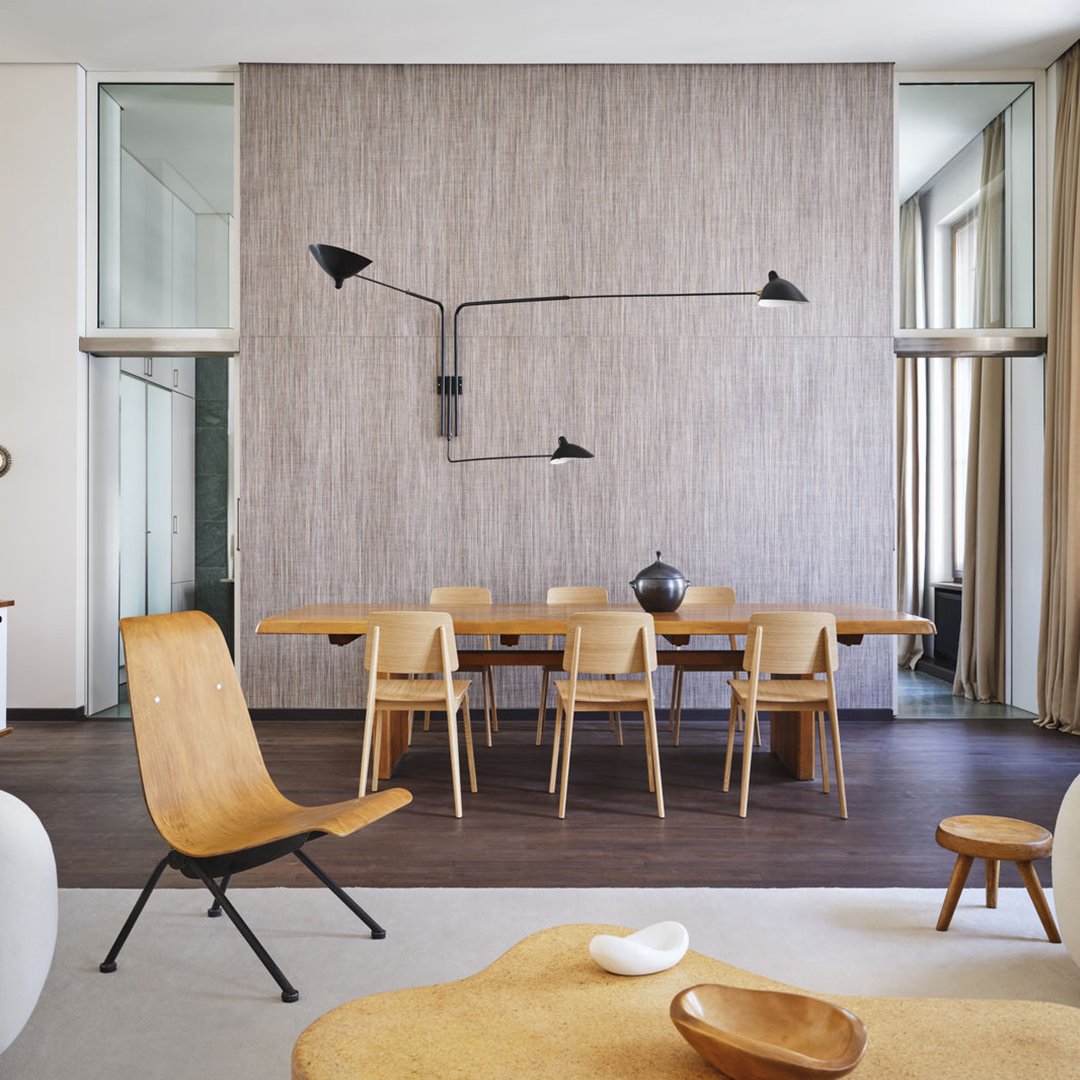Stylish wooden dining set with sleek black lighting and a textured neutral wall, complementing warm tones and organic shapes.
