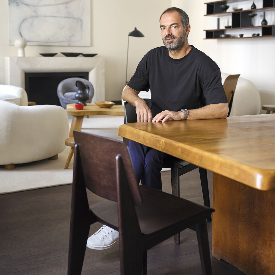 Black t-shirt with a minimalist design, paired with dark wooden furniture and a neutral-toned interior setting.