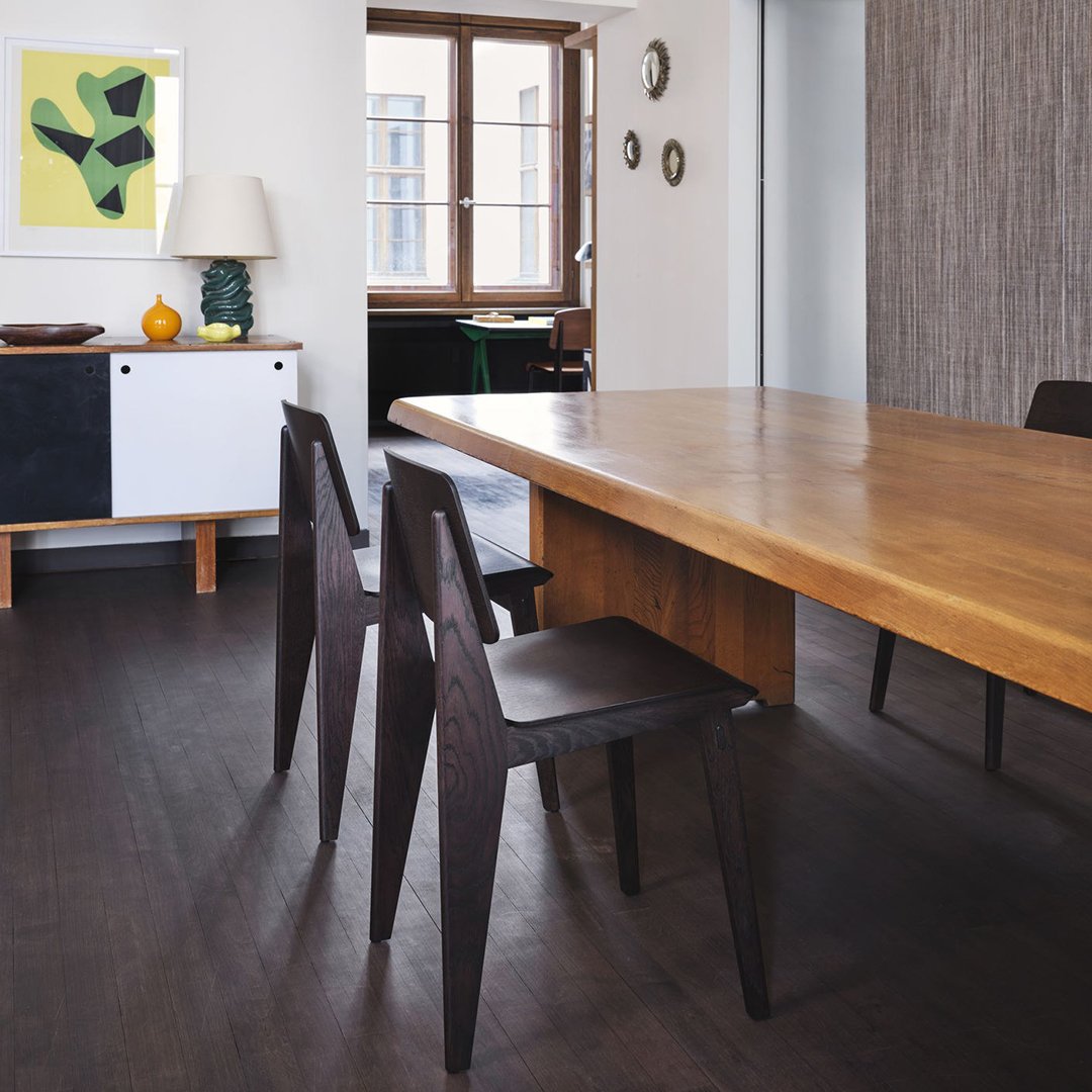 Modern wooden dining table with dark chairs, featuring a neutral color scheme and crisp, minimalist lines.