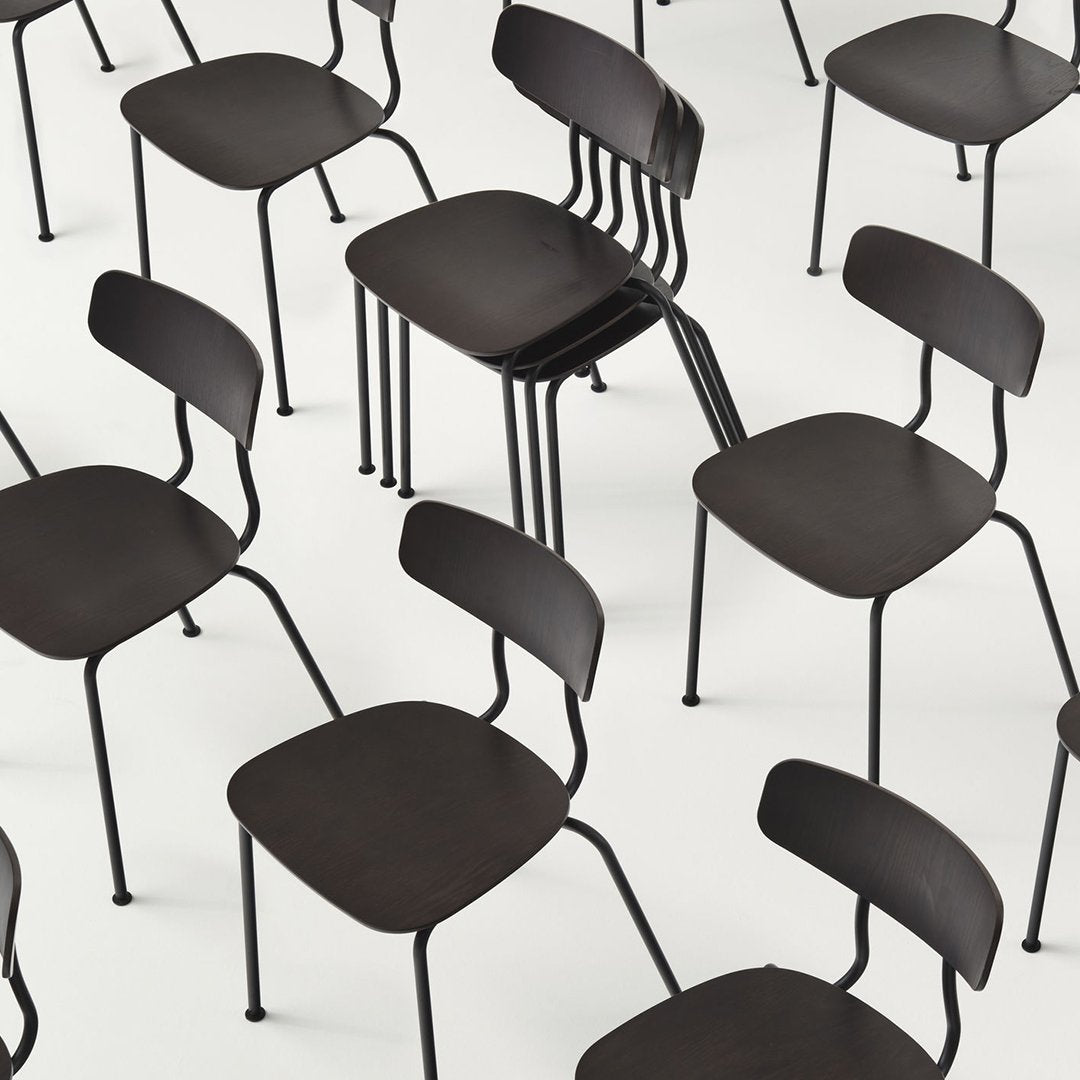 Black modern chairs with minimalist design, featuring sleek curves and a matte finish, arranged in a dynamic pattern.
